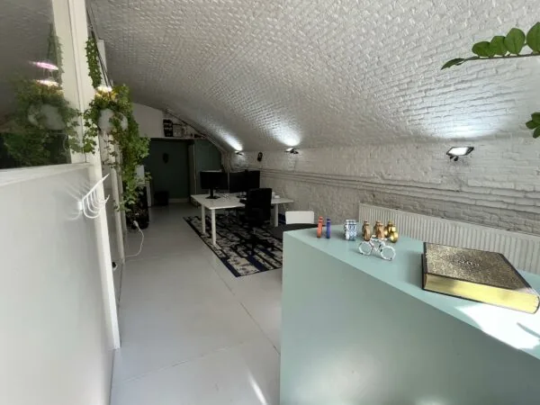 Modern ingerichte werkruimte in een tunnelvormige ruimte met witte bakstenen gewelven en decoratieve elementen op de balie.